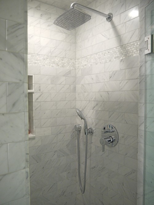 Marble subway tile shower with marble mosaics inset