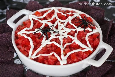 Spider web on a bowl of salsa or red dip for halloween, decorated with a little sour cream and a couple of plastic spiders