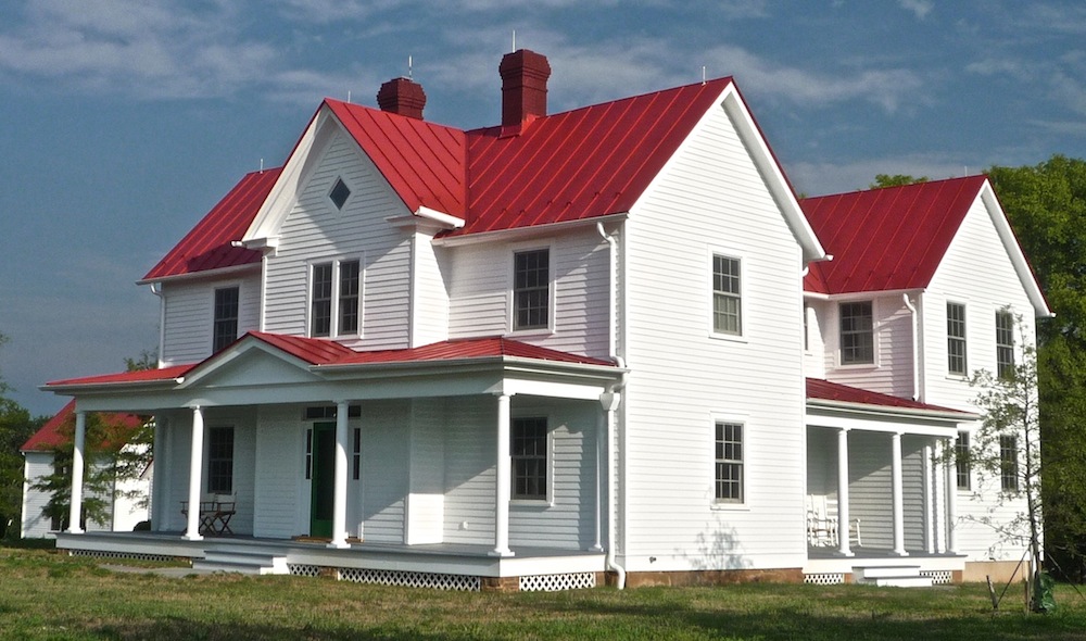 Classic white farmhouse with a red metal roof. Celebrate & Decorate