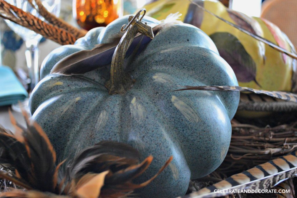 A blue pumpkin and pheasant feathers whisper that Fall is coming. They will be decorating a Fall table.