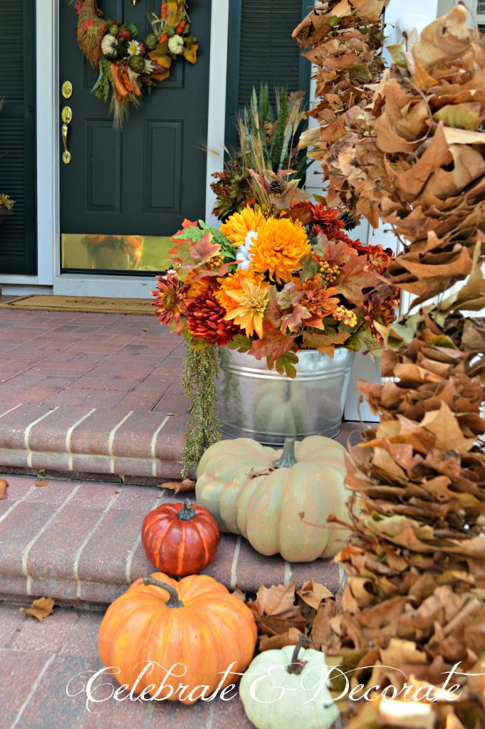 Galvanized tubs of faux fall flowers and leaves add to the farmhouse feel of this Fall front porch