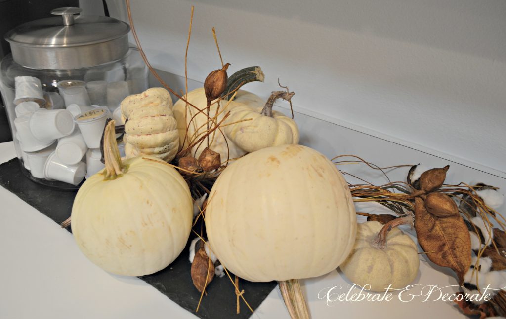 White pumpkins and cotton boll garlands tumble along the kitchen counter atop a slate board.