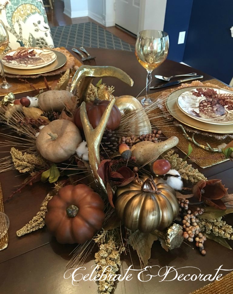 Golden Fall tablescape with a centerpiece of pumpkins and golden antlers. 