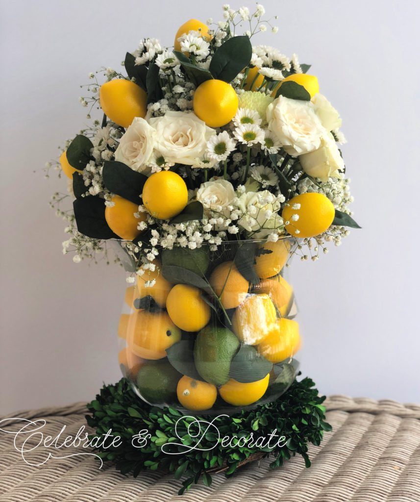 A centerpiece of lemons and limes in a glass vase with white flowers