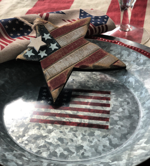 A galvanized plate with a flag motif on it and a wooden red, white and blue rustic star.