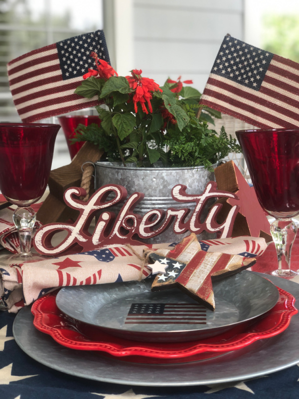 A galvanized plate with a flag motif on it and a wooden red, white and blue rustic star.