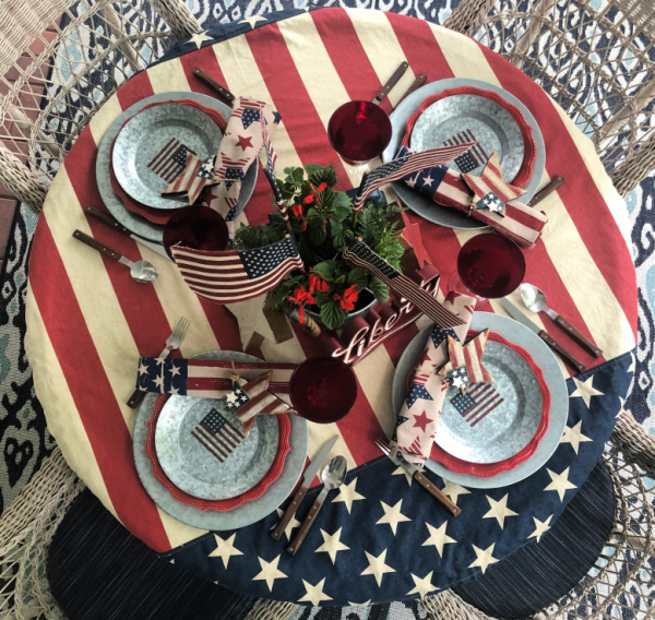 A round table decorated with a patriotic tablecloth and vintage style table setting.  