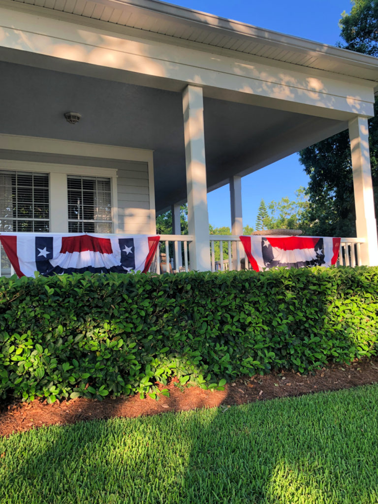 Red white and blue banners decorate a wrap around porch
