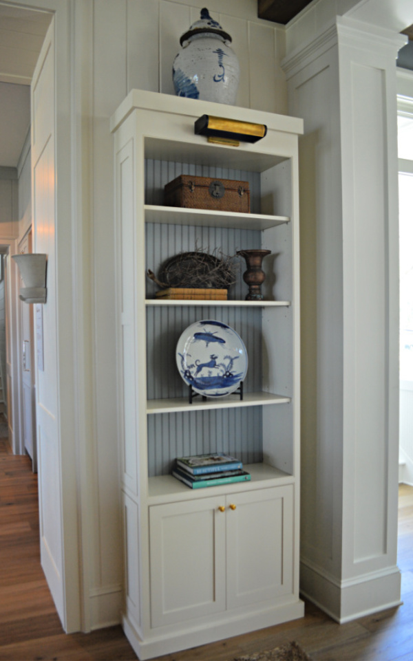 White bookshelf backed with blue bead board with blue and white accessories