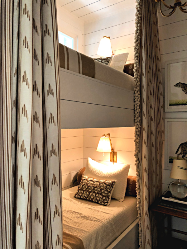 A dressy elegant bunk room has neutral color curtains with heavy fringe
