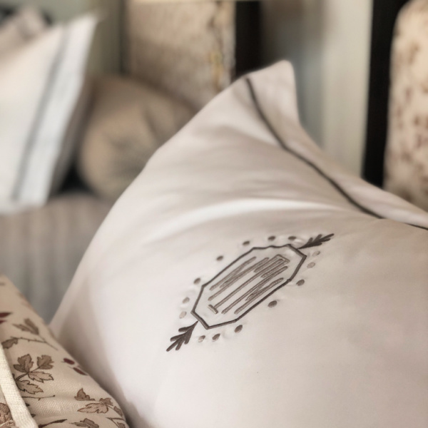 Monogrammed linens on a bed dressed in neutral colors 