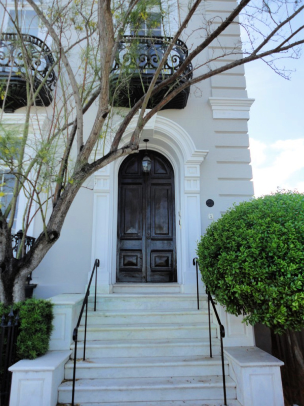 Elegant Charleston home with steps up to the front door with a dark wood arched front door.