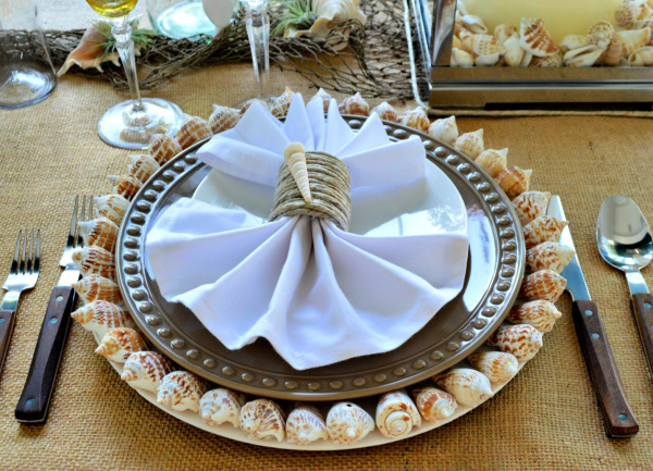 Seaside place setting with neutral colors and seashell chargers and seashell napkin rings
