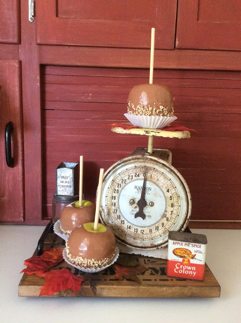Caramel apples on display on a vintage kitchen scale.