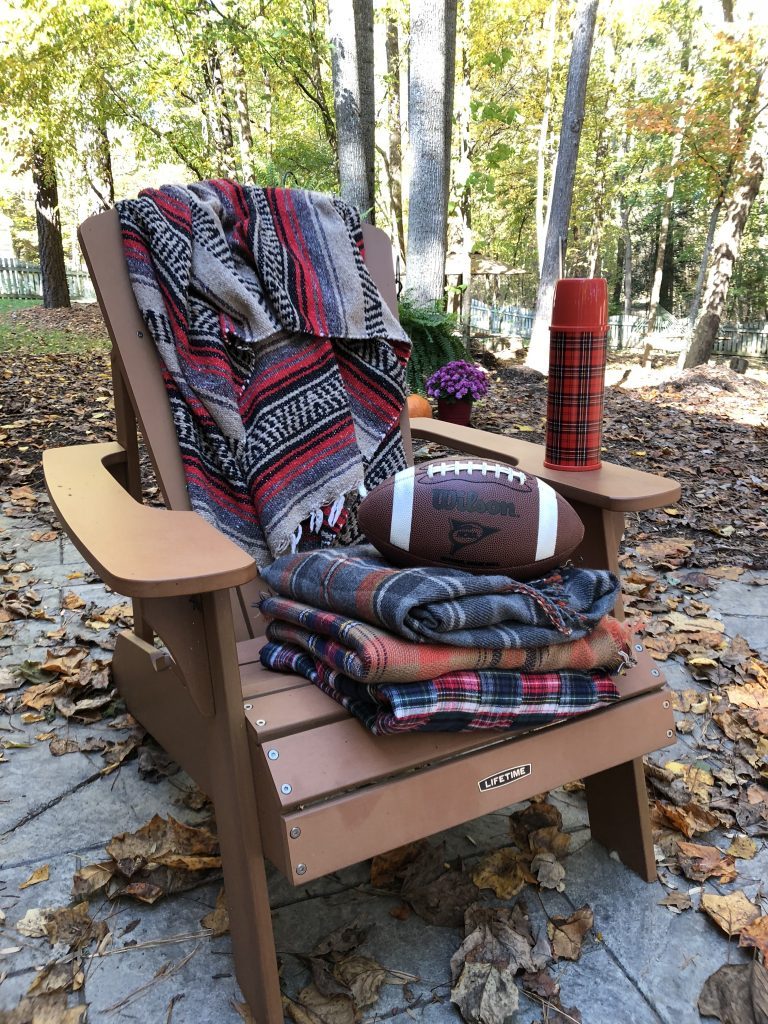Adirondack chair with fall blankets and a football ready to get cozy for Fall 