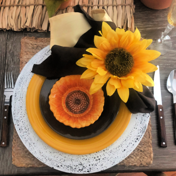 A sunflower table setting with yellow and brown plates and sunflower napkin rings