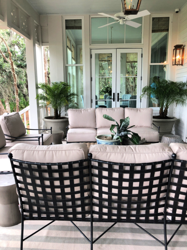 Beautiful back porch with comfy furniture and palms in pots