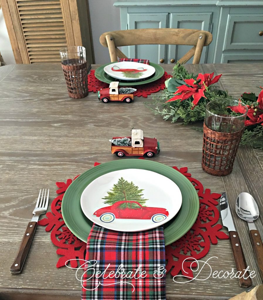 Christmas tablescape with little red trucks with Christmas trees in the back of the trucks