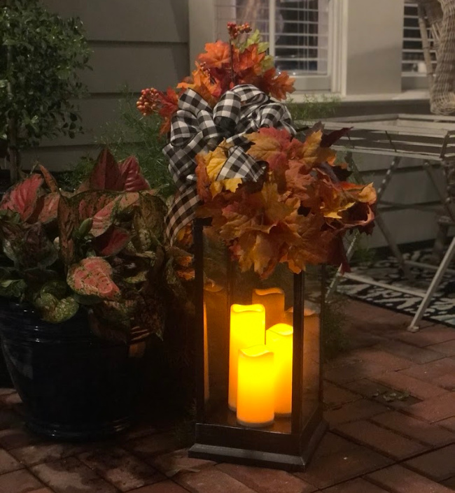 Fall lantern at night with fall leaves and buffalo check bow