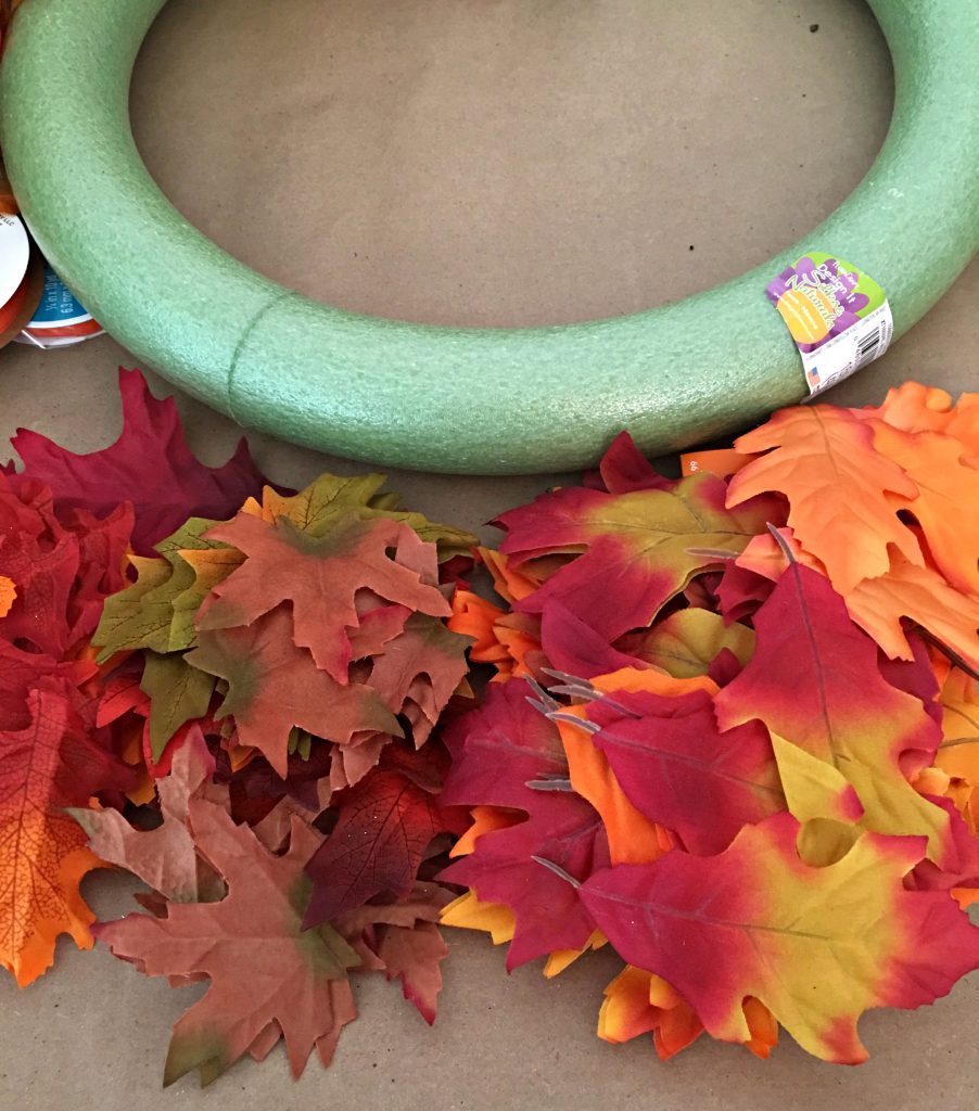 A green styrofoam wreath and faux . fall leaves