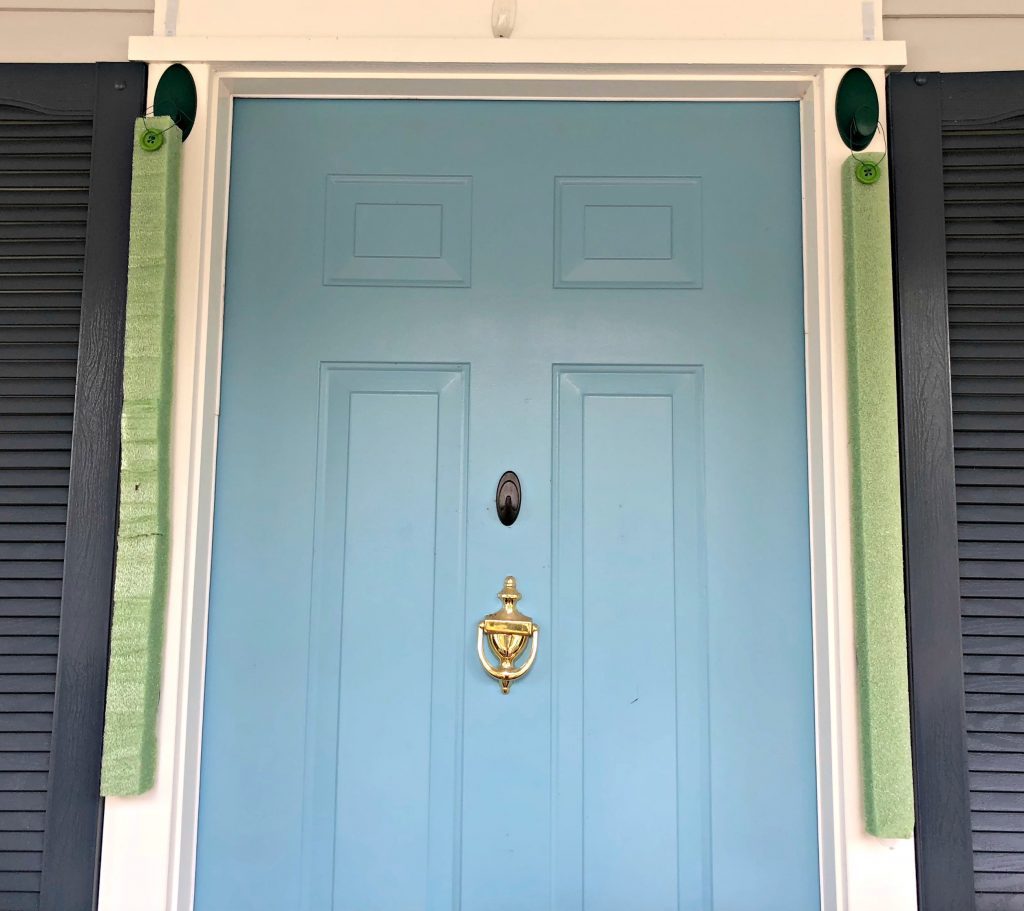 Strips of styrofoam hung next to a blue front door. 