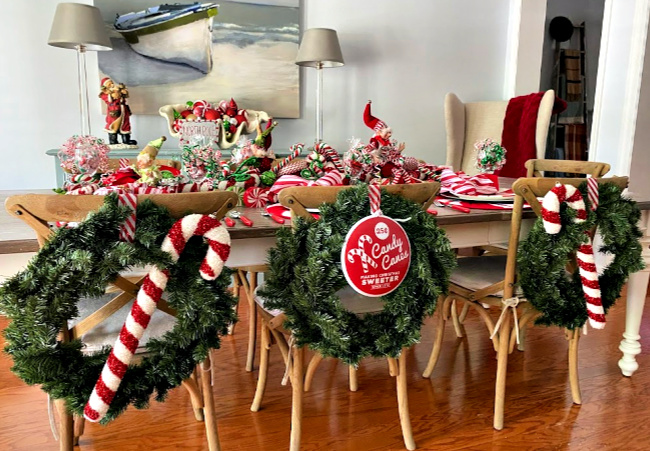 The back of chairs decorated with candy canes and wreaths for a holiday table.