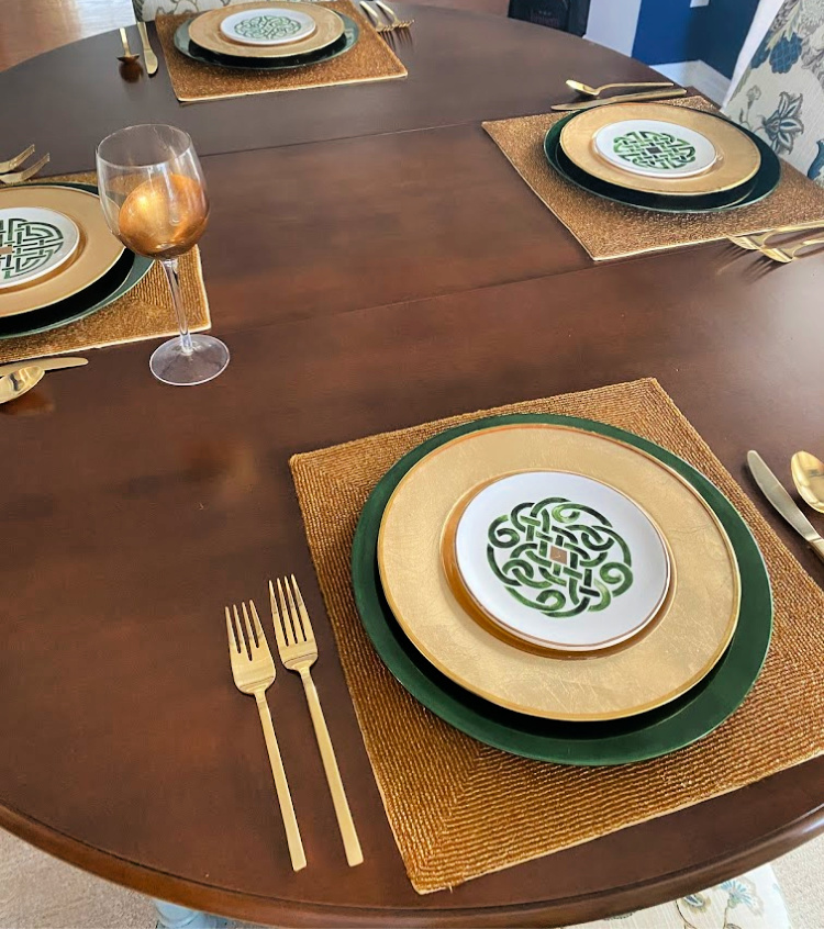 Dark wooden table with place settings in green and gold for St. Patrick's Day