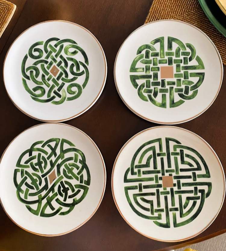 Set of 4 salad plates that are white with a gold rim and gold accents with green celtic knot patterns on them