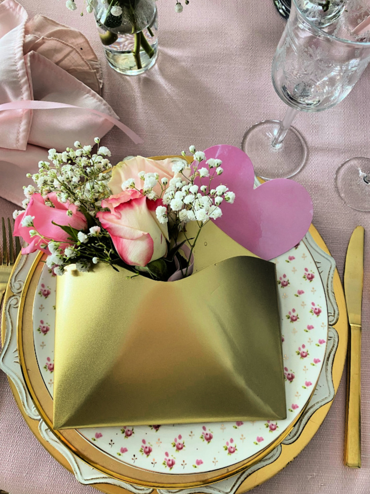 Valentine plate stack with a gold envelope filled with pink roses