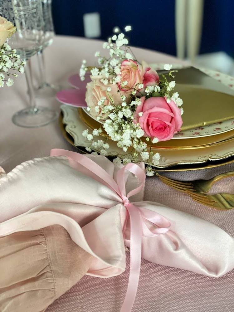 Two toned pink napkins tied with a pink ribbon and pink roses.