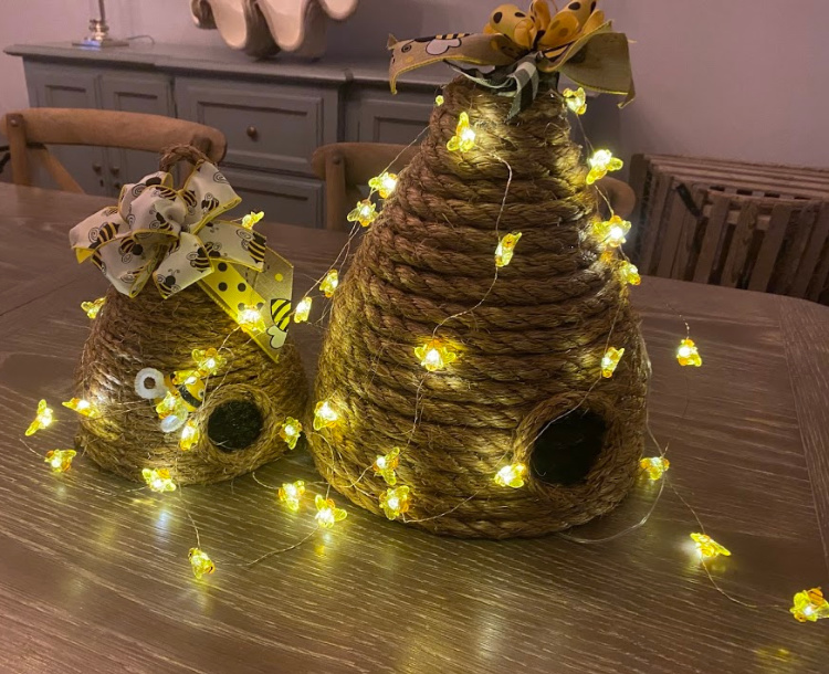 Two diy bee skeps made with jute rope and lit with battery operated little bee lights