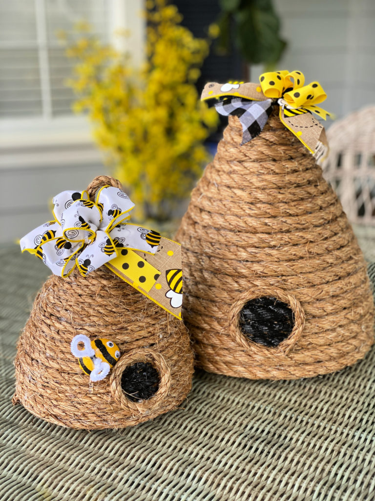 Two diy bee skeps made from jute rope and trimmed with bee themed ribbons