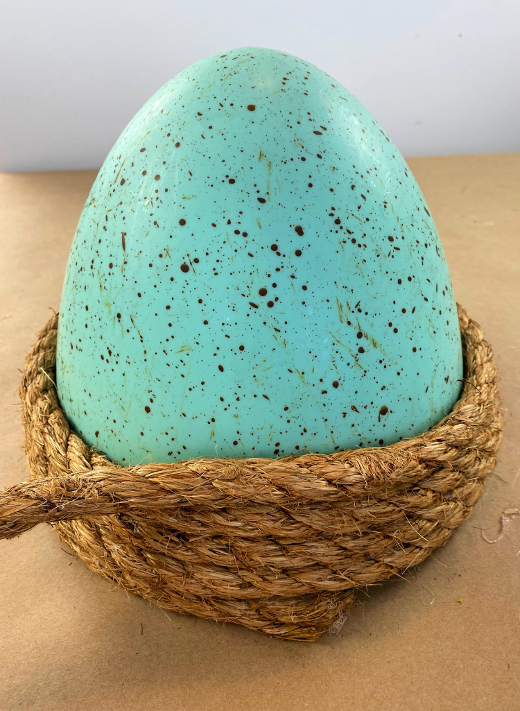 A large blue speckled easter egg with jute rope wrapped around the bottom of it.