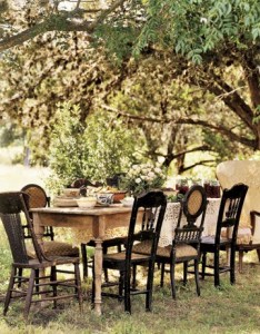 Alfresco dining at a rustic table with mismatched chairs.