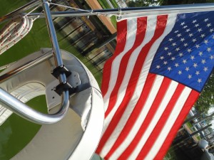 American Flag flying behind a sailboat behind the horseshoe life preserver.