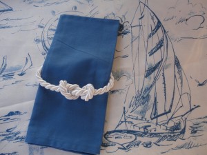 Nautical napkin ring on fabric with sailboat print.