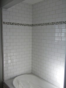 Subway tile shower with inset of small gray mosaics