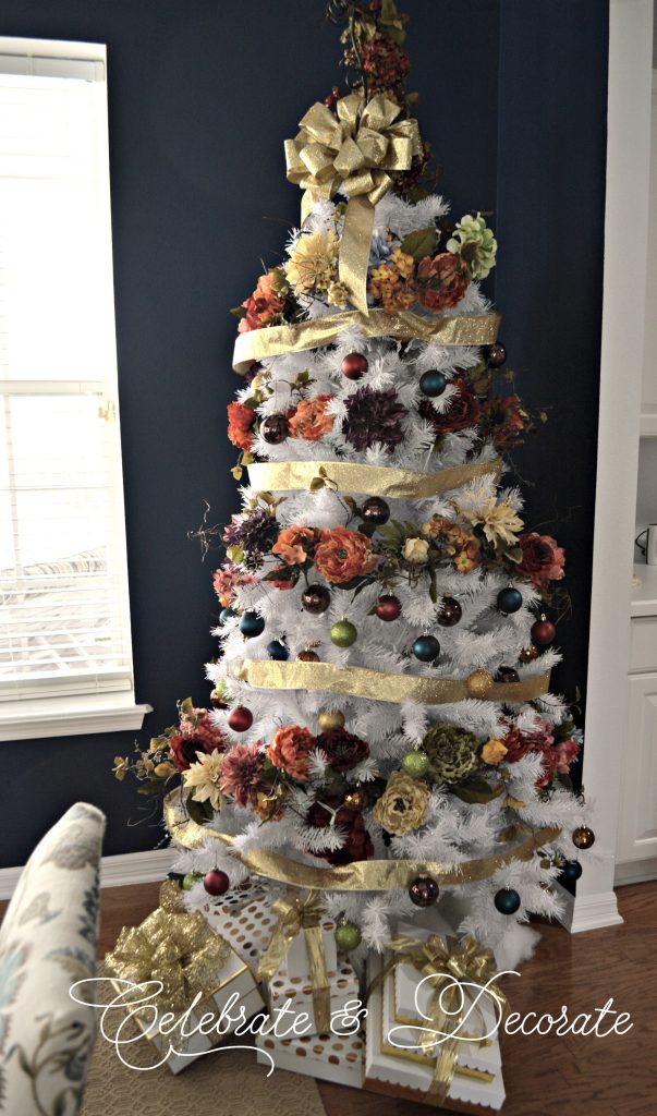 A White Christmas tree decorated with garlands of jewel tone flowers. 
