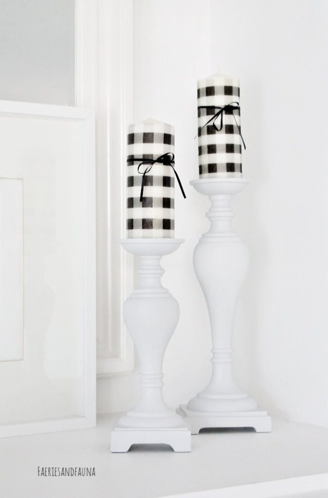 A pair of black and white buffalo check candles atop a pair of crisp white candleholders