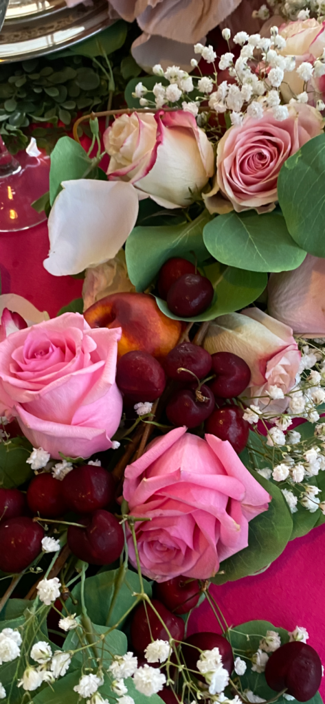 a close up photo of pink roses and cherries and baby's breath