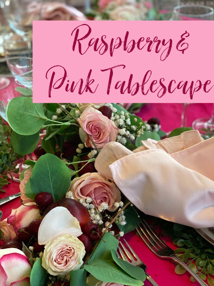 A photo of a tablescape with greenery, pink roses and pink napkins.  Words over the photo that say a raspberry and pink tablescape
