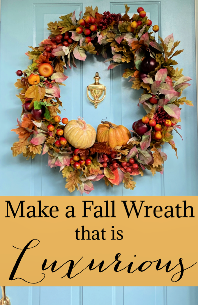 Luxurious fall wreath filled with autumn leaves, berries, apples, and pumpkins displayed on a light blue front door.