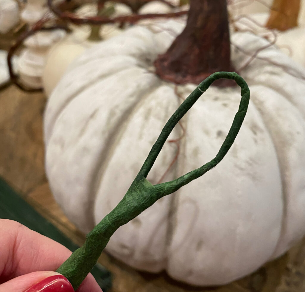 white pumpkin in the background with green floral wire with floral tape on it
