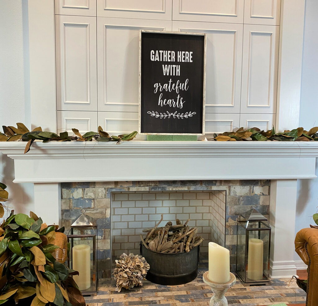 white fireplace and mantel with black and white sign and magnolia leaves