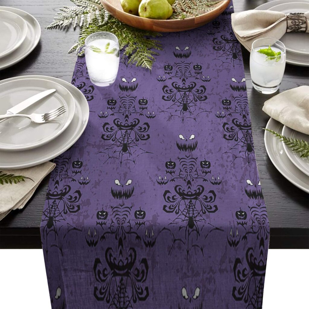 A table set with white dishes and a purple and black spooky table runner.