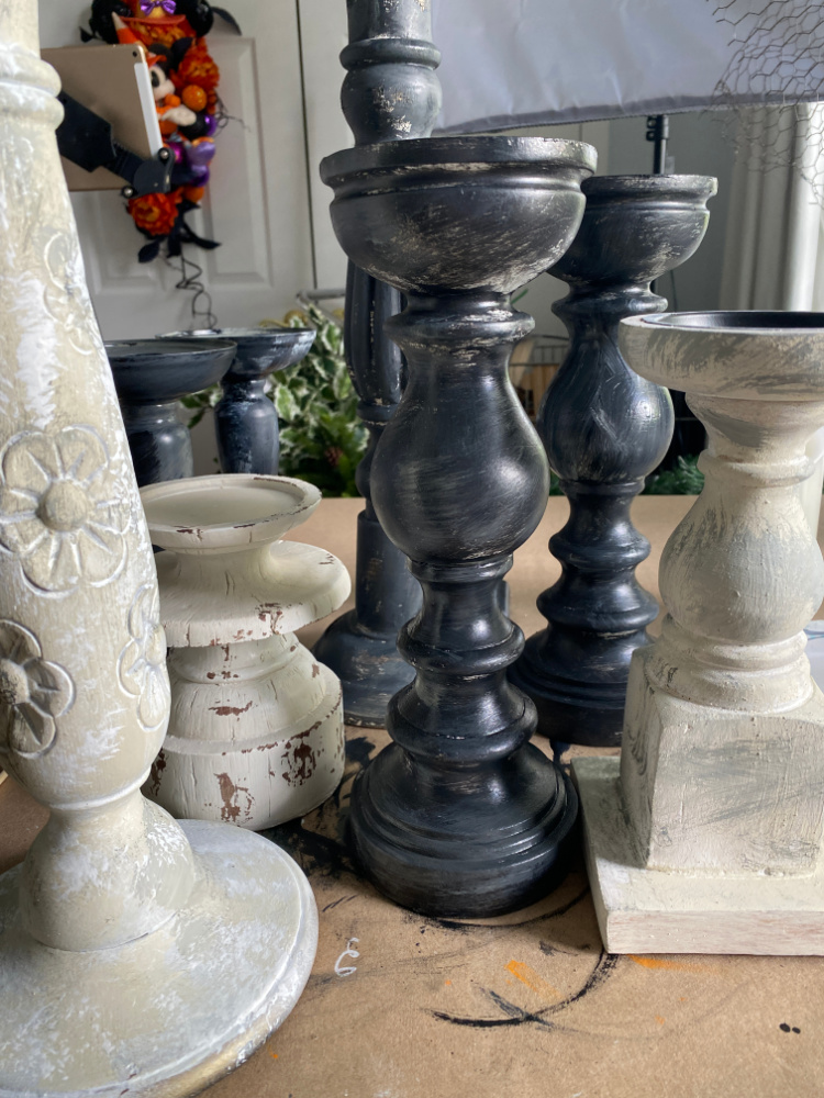 Tall wooden candlesticks that are distressed and being painted black.