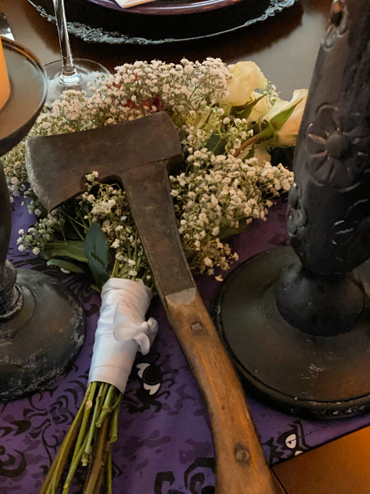 An old axe resting on a bouquet of white roses and babies breath