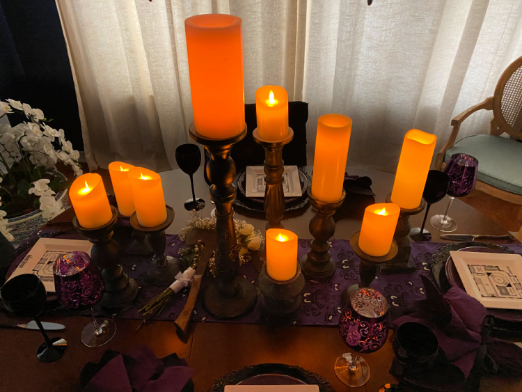 An over head view of a halloween table with large candles lit and spread down the center of the table.  