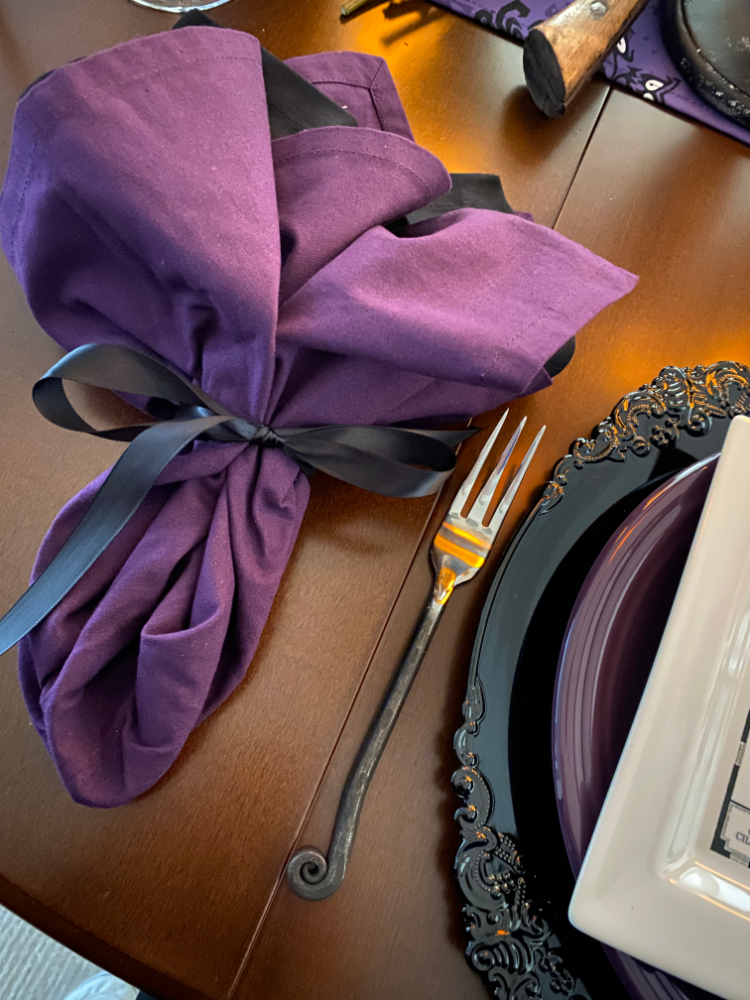 A purple napkin tied with a black bow.