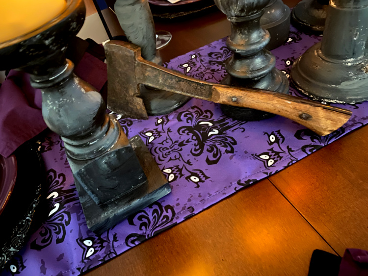 An old axe resting on a purple and black table runner